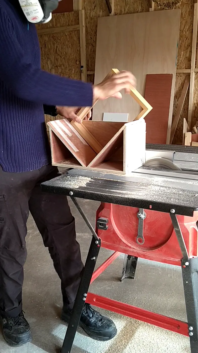 The wooden frame cutting splines on a table saw.
